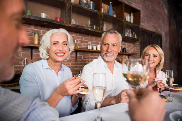 Gelukkige aangename mensen praten over wijn rond de tafel — Stockfoto