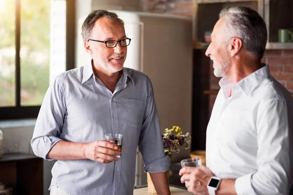 Ontspannen oude vrienden drinken whisky in de keuken — Stockfoto