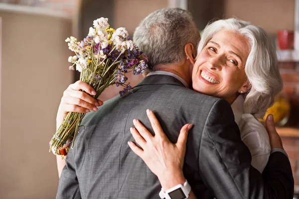 Atractiva abuela sonriendo a la cámara mientras abraza a su marido — Foto de Stock