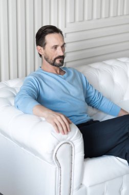 güvenle kanepede oturan adam