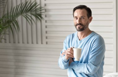 bir çay bardağı tutan iyimser adam