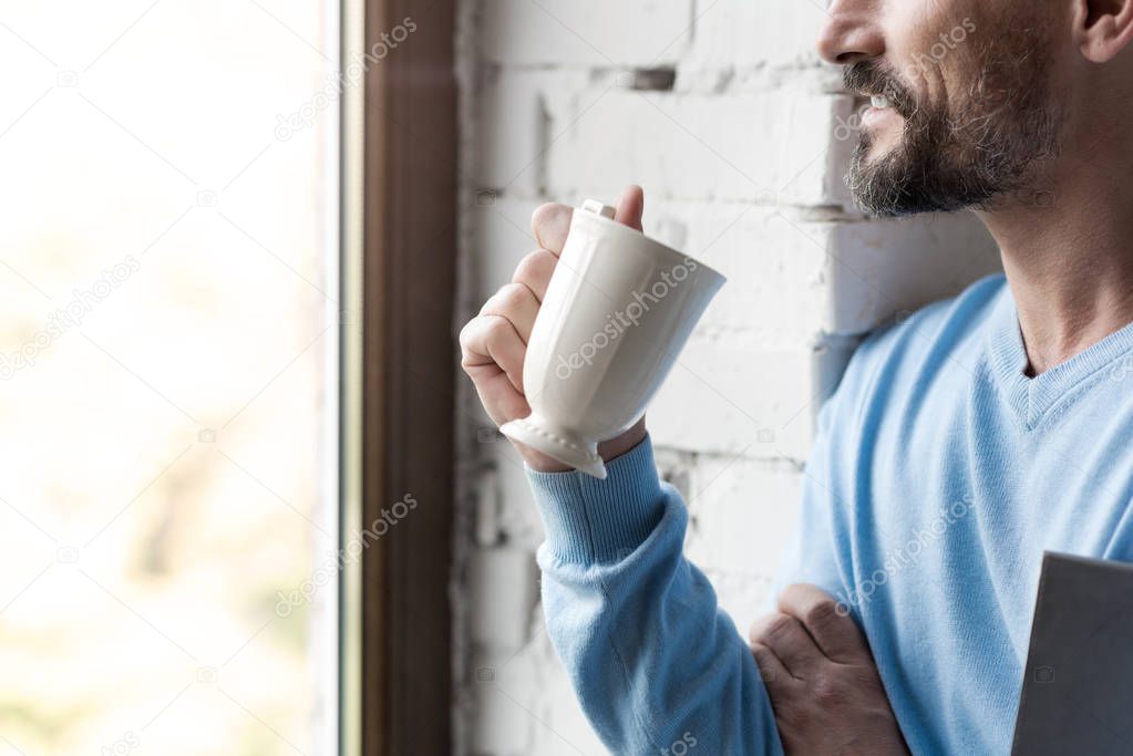 Pleasant joyful man drinking coffee