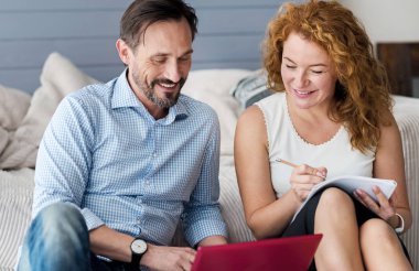 Dizüstü bilgisayar kullanarak ve notlar gülümseyen Çift