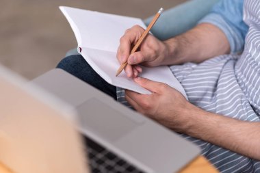 Genç adamın notlar laptop yanında yapım yakın çekim.