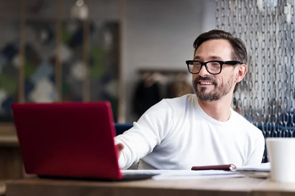 Bebaarde man met bril die op laptop werkt — Stockfoto