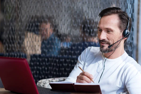 Bearded man looking at laptop and talking notes — Stock Photo, Image