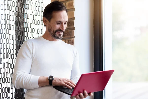 Vousatý muž stojí a drží notebook — Stock fotografie