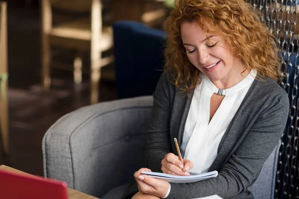 Ansicht einer lächelnden Frau, die Notizen macht — Stockfoto