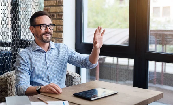 Smiling gesturing hello with his hand — Stock Photo, Image