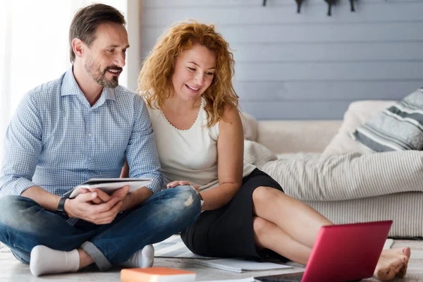 Nice couple sitting in floor and looking at laptop — Stock Photo, Image