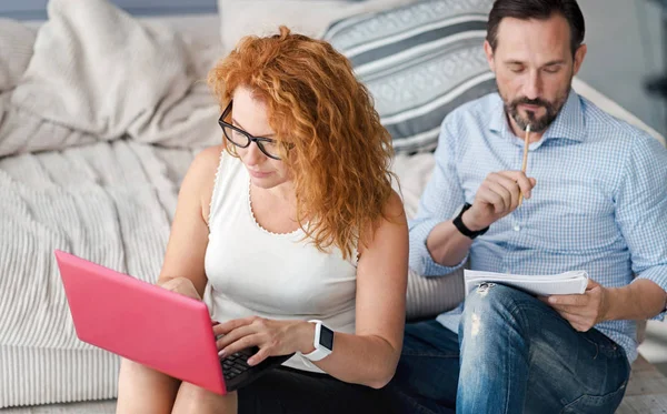 Mulher trabalhando com laptop enquanto o homem toma notas — Fotografia de Stock