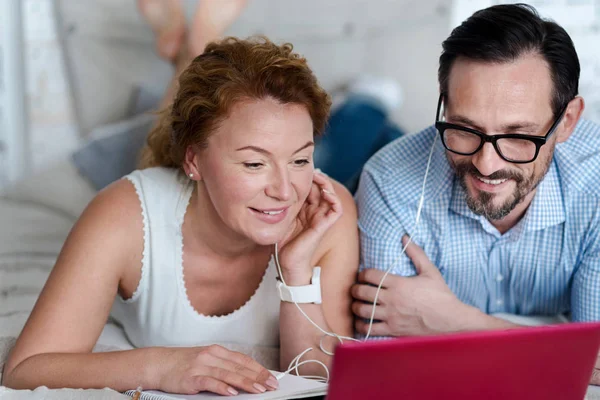 Man and woman sharing earphones while lying on bed