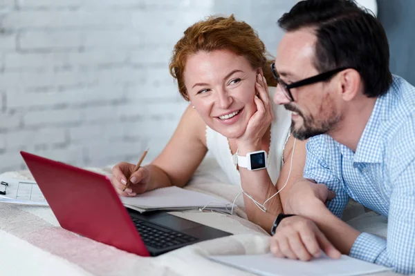 Man and woman sharing earphones while lying on bed — Stock Photo, Image