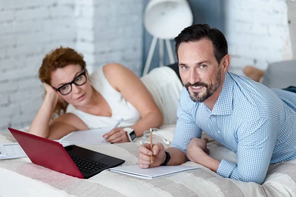 Bärtiger Mann macht sich Notizen, während er mit Frau im Bett liegt — Stockfoto