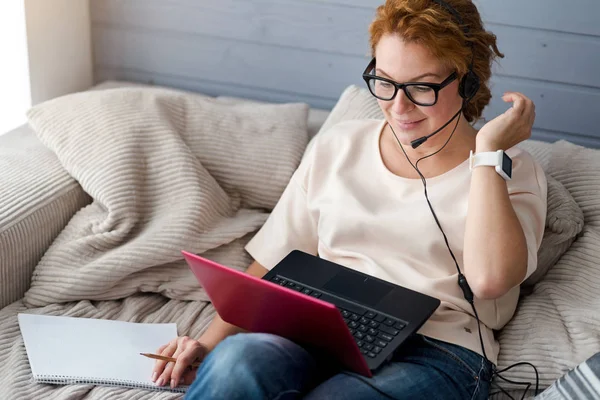 Mulher no sofá com laptop fazendo anotações — Fotografia de Stock