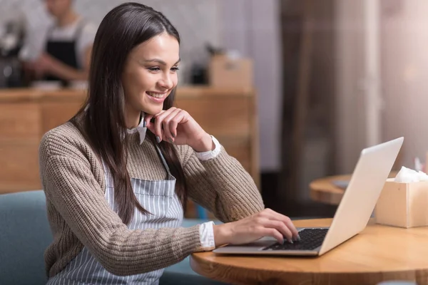 Χαμογελώντας όμορφη νεαρή γυναίκα που εργάζεται σε φορητό υπολογιστή. — Φωτογραφία Αρχείου