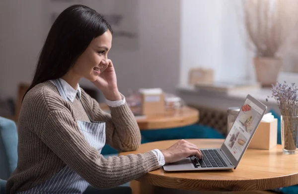 Glad vacker kvinna med hjälp av mobiltelefon och arbetar på bärbar dator. — Stockfoto