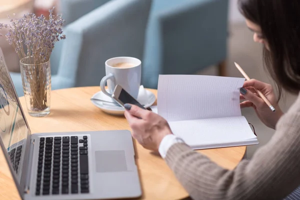 Närbild på ung kvinna att göra anteckningar och använda laptop. — Stockfoto