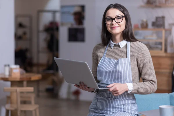 Fermecătoare tânără femeie care deține laptop și zâmbind . — Fotografie, imagine de stoc