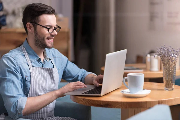 Smiling pleasant young man using laptop. — Stock Photo, Image