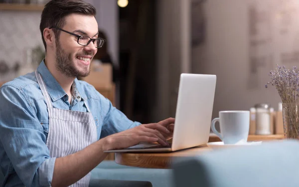 Uśmiechający się zadowolony człowiek pracuje na laptopie. — Zdjęcie stockowe