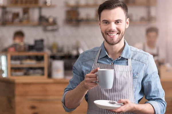 Pozytywny człowiek uśmiechający się trzymając kubek kawy. — Zdjęcie stockowe
