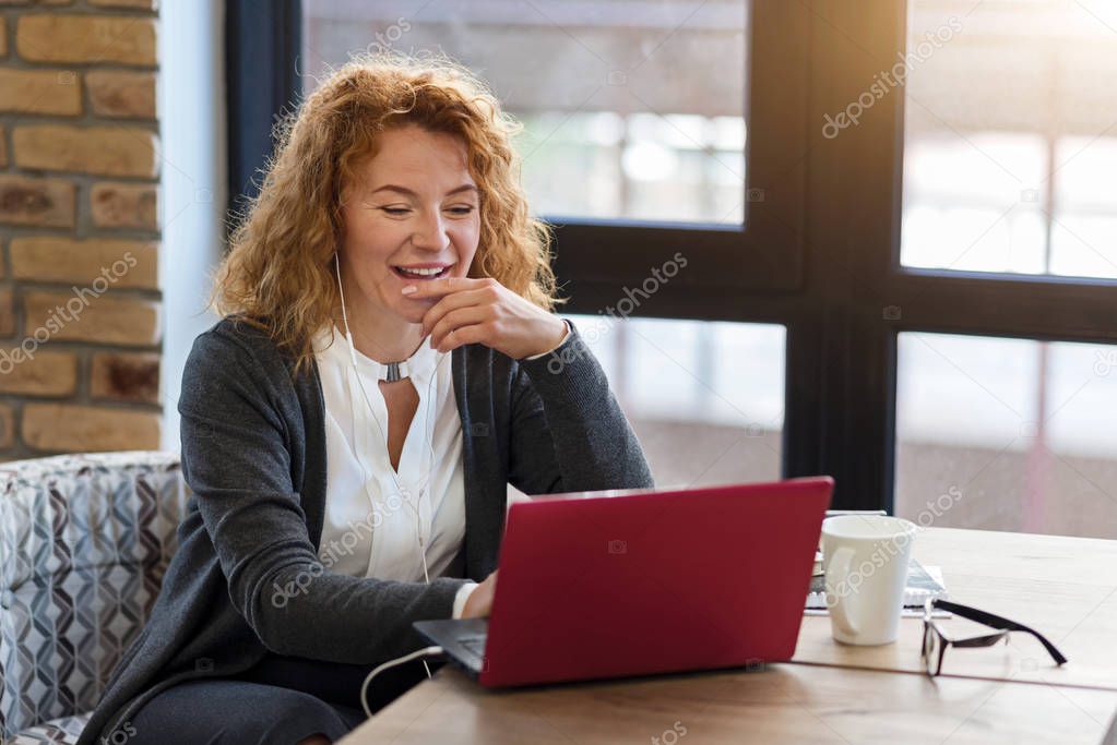 Happy woman using laptop in cafe