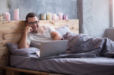 man using his laptop in  bed clipart