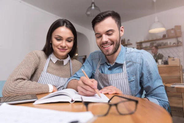 Encantador casal sorrindo e trabalhando à mesa . — Fotografia de Stock