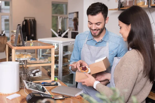 Smiling waiters putting cakes into the box. — Stock Photo, Image