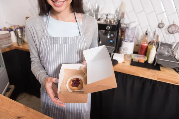 Hermosa camarera sonriente presentando pastel en un café . — Foto de Stock