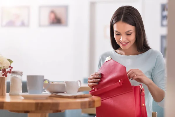 Piękna kobieta uśmiechający się sprawdzanie jej torbę w kawiarni. — Zdjęcie stockowe