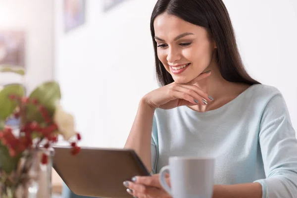 Schöne junge brünette Frau mit einem Gadget beim Entspannen. — Stockfoto