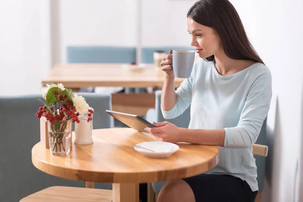 Joyeux belle femme prenant un café et en utilisant son gadget . — Photo