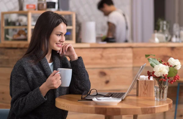 Vidám vonzó nő használ a laptop egy kávézóban. — Stock Fotó