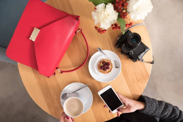 Frau benutzt Handy und trinkt Kaffee. — Stockfoto