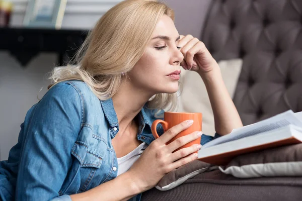 Close up of reading woman with cup — Stock Photo, Image