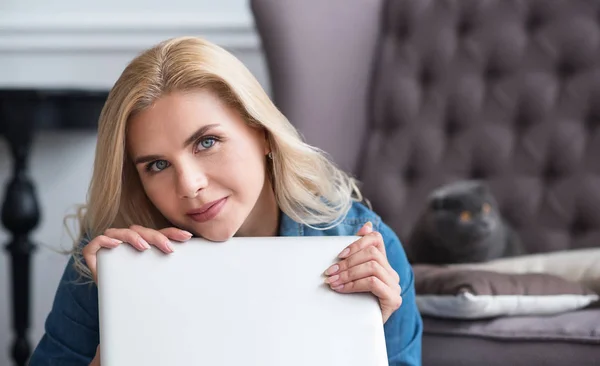 Verträumte blonde Frau umarmt Laptop — Stockfoto
