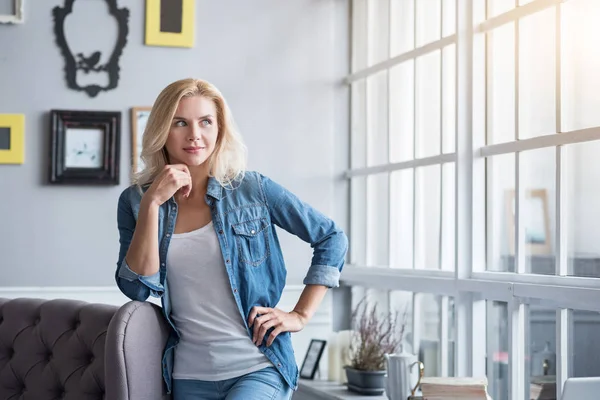 Mujer rubia apoyada en un sofá gris — Foto de Stock