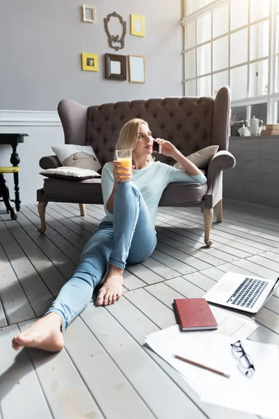 Blonďatá žena sedí na podlaze a mluví za telefon — Stock fotografie