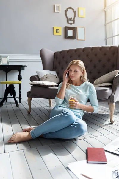 Blond kvinna sitter på golvet och pratar per telefon — Stockfoto