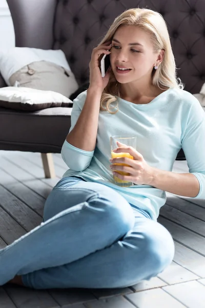 Блондинка держит стакан сока и говорит по телефону — стоковое фото