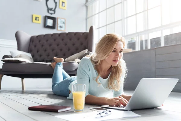 Blond kobieta, leżąc na podłodze i przy użyciu laptopa — Zdjęcie stockowe