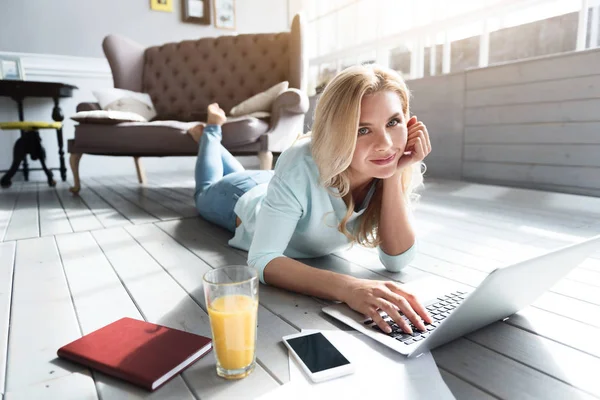 Blond kobieta, leżąc na podłodze i przy użyciu laptopa — Zdjęcie stockowe