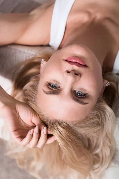 Lähikuva blondi nainen makaa sängyllä — kuvapankkivalokuva