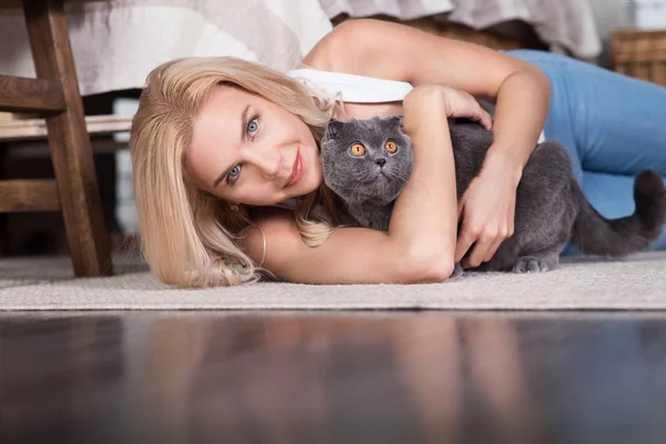 Женщина лежит на полу с котом — стоковое фото