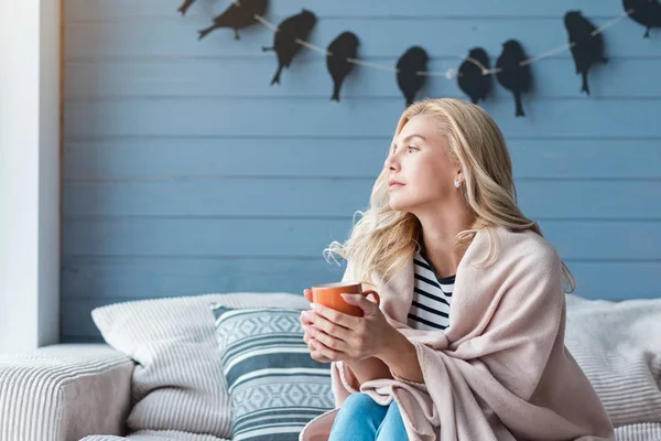 Woman sitting on sofa with cup — Stock Photo, Image