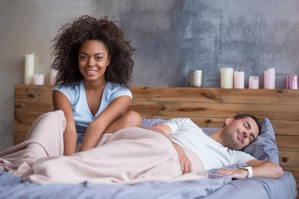 Chica sonriendo mientras su marido está durmiendo — Foto de Stock