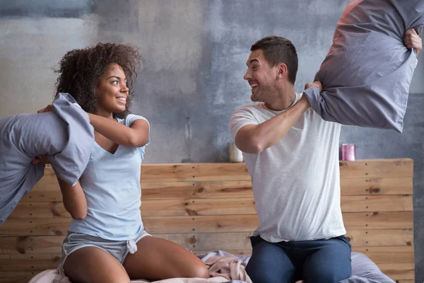 Sonriente pareja luchando con almohadas —  Fotos de Stock