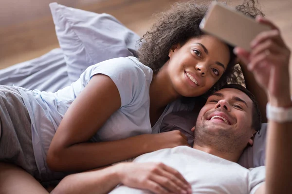 Pareja tomando fotos juntos en la cama — Foto de Stock